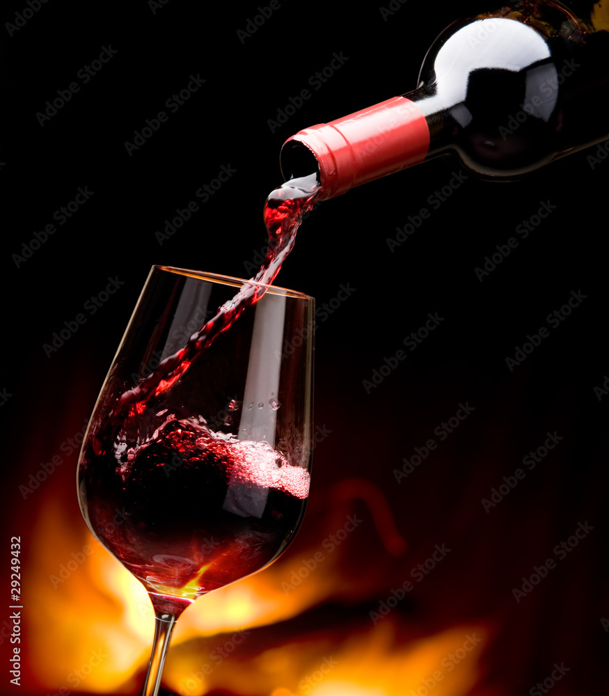 Fototapeta pouring wine by the fireplace