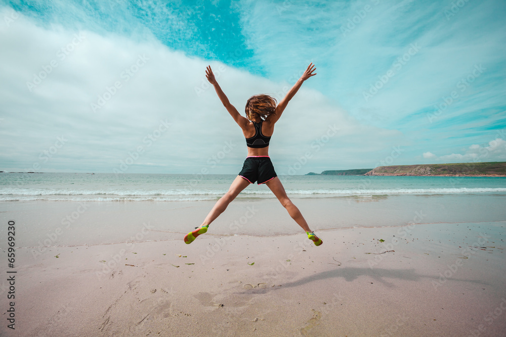 Fototapeta Young woman doing star jumps